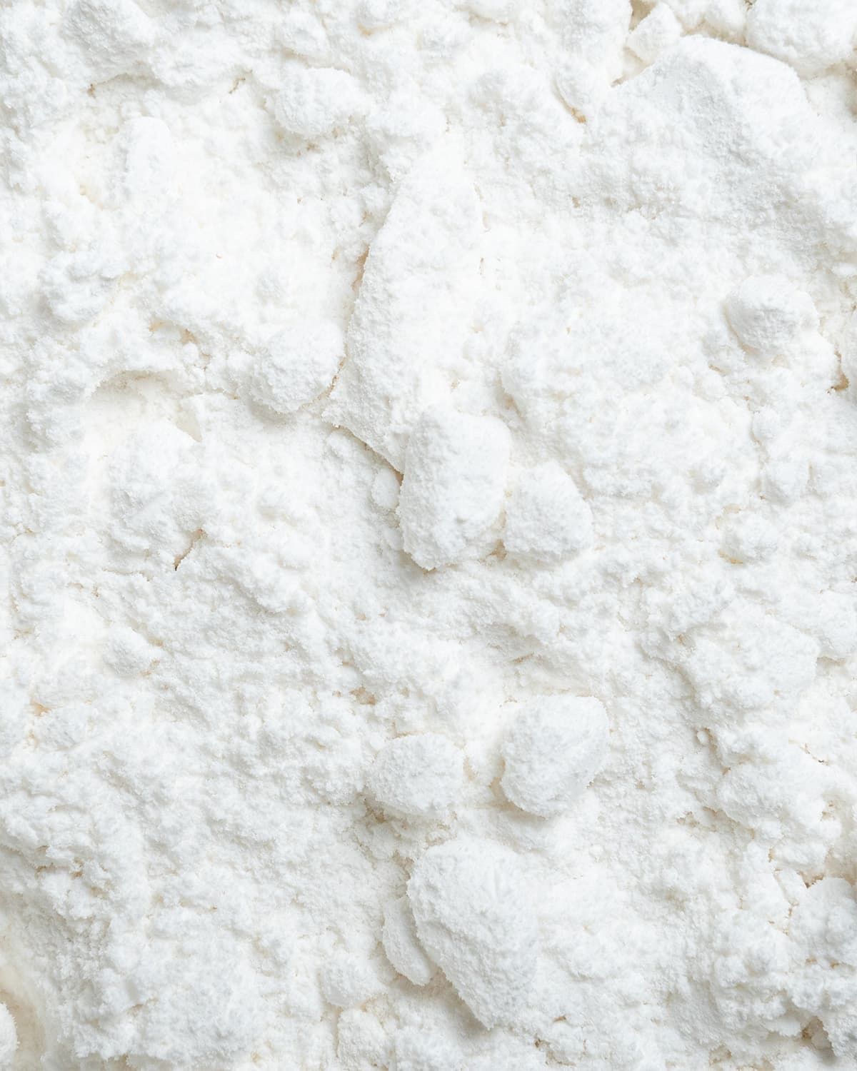 Close-up of white D-Mannose powder with small clumps.