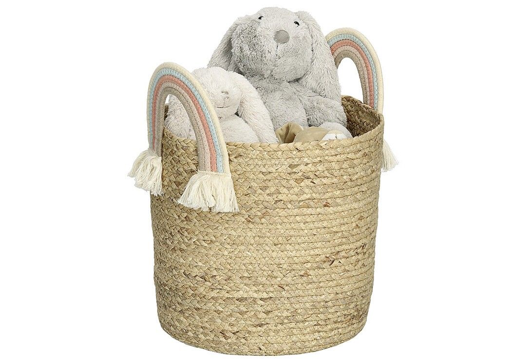 Runder Aufbewahrungskorb aus Naturmaterial mit Regenbogen-Henkeln. Gefüllt mit zwei Stofftieren. Fransen an den Henkeln.
