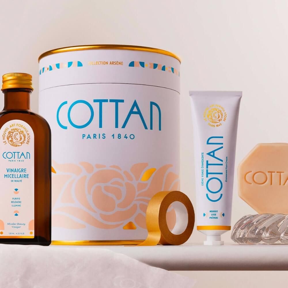 Geschenkset mit Dose, Flasche, Creme, Seife und Klebeband. Aufschrift COTTAN. Weitere Produkte mit Text.