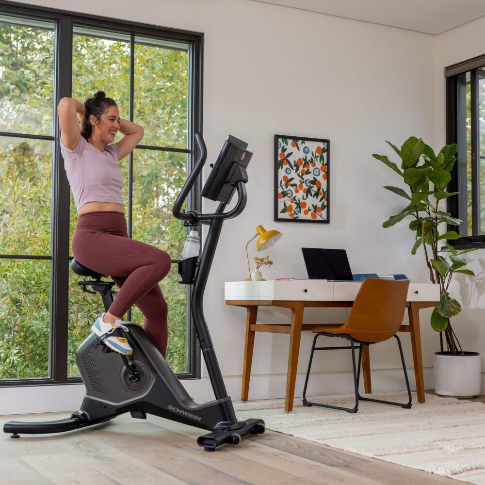 Frau trainiert auf einem Hometrainer. Schwinn Fitness 590U. Wasserflasche am Lenker.