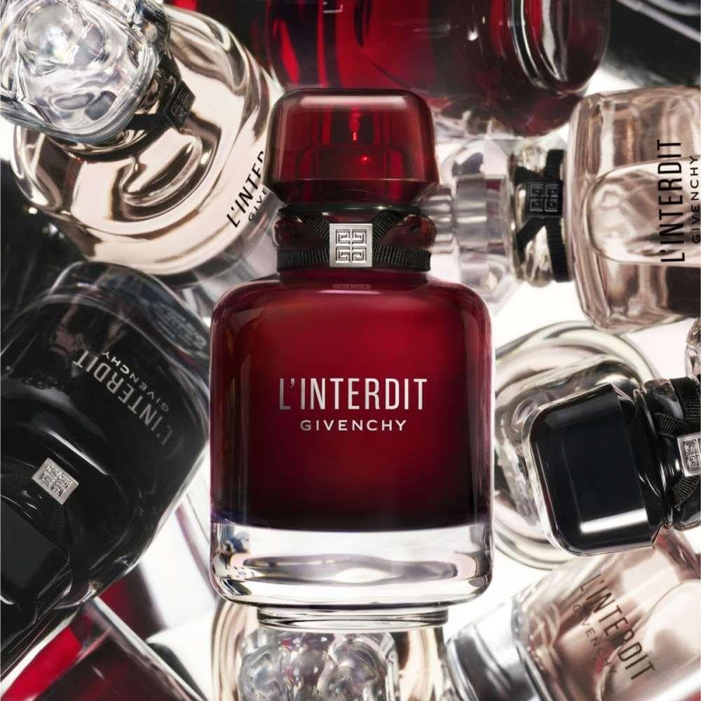 Roter Flakon, umgeben von anderen Parfümflakons. Aufschrift: L'Interdit Givenchy. Flakon mit silbernem Boden.