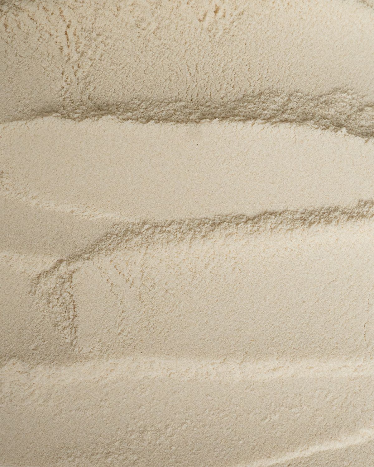 Nahaufnahme von Xanthan Gum Pulver mit wellenförmigen Texturen.