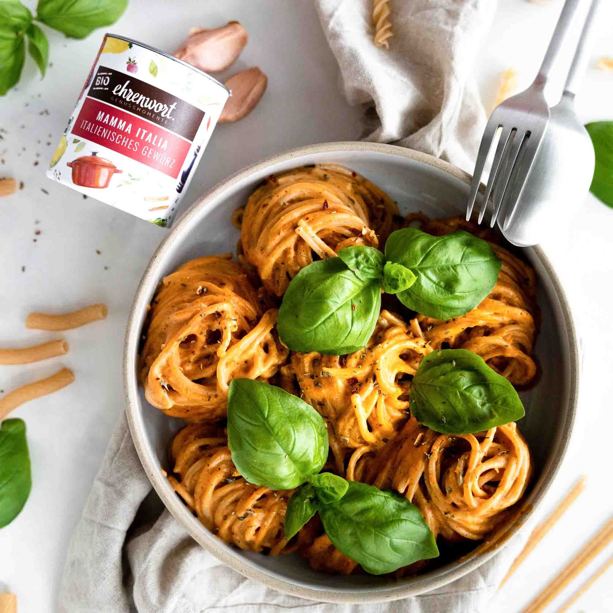 Bio Mamma Italia Gewürz in einer Dose neben einer Portion Pasta mit Basilikum.