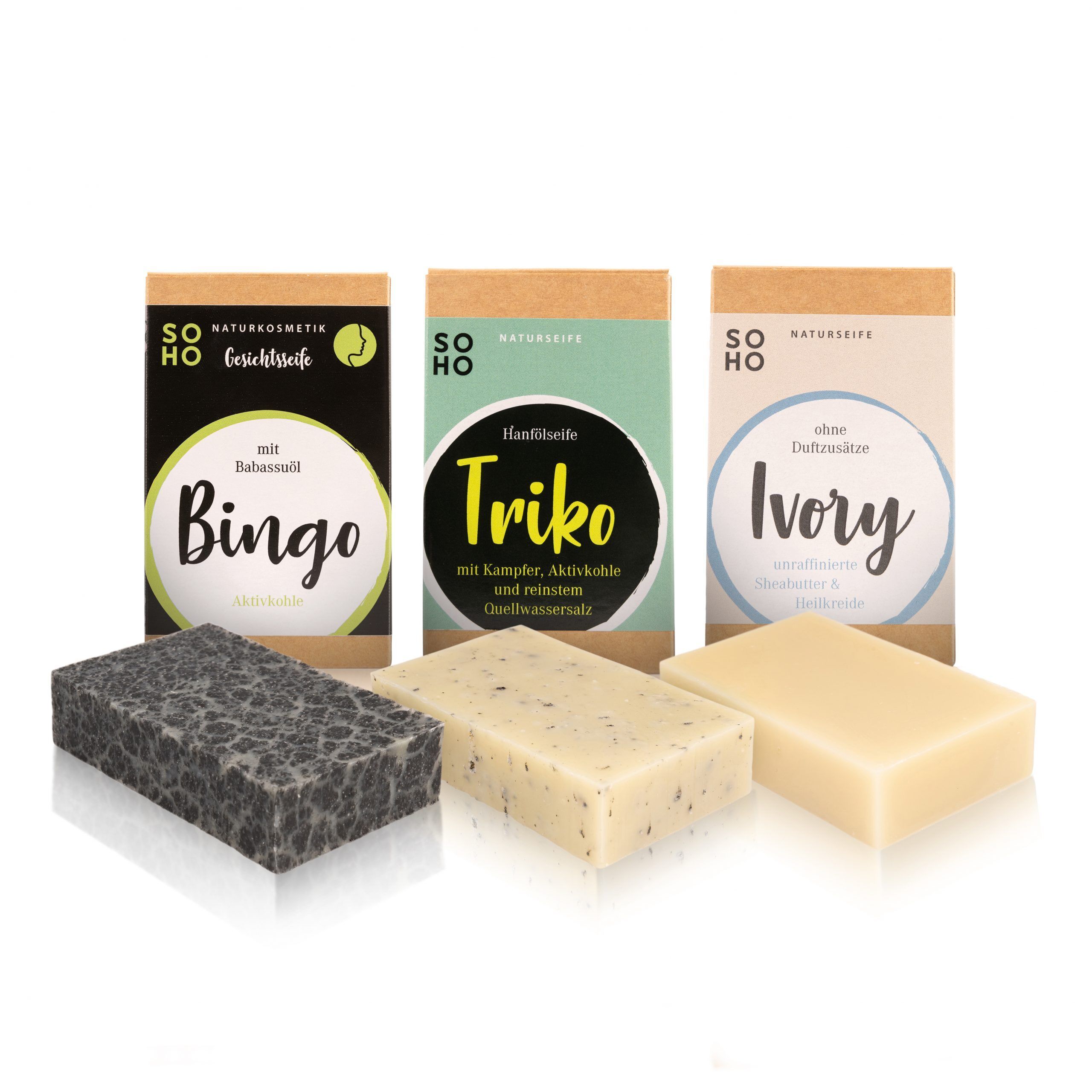 Drei Seifenstücke und Verpackungen. Aufschrift: SOHO Naturkosmetik. Seifen: Bingo, Trik, Ivory. Verpackungen aus Karton.