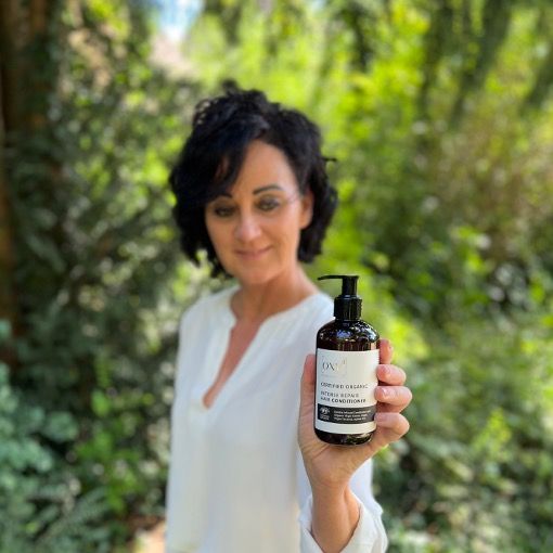 Frau hält Produktflasche. Text: INTENSE REPAIR HAIR CONDITIONER. Braune Flasche mit schwarzem Pumpkopf.
