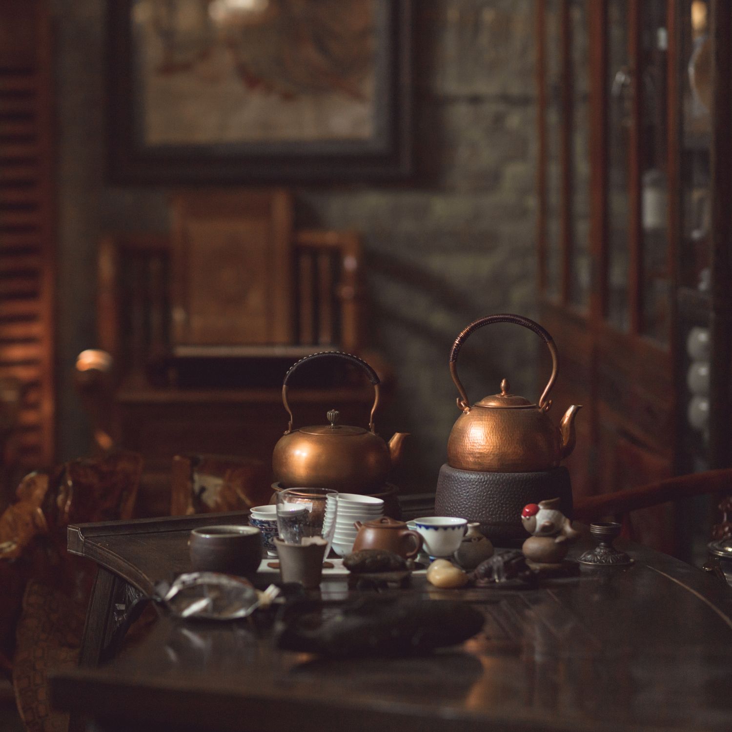 Zwei Kupferkessel auf einem Tisch, umgeben von Tassen und Tellern. Im Hintergrund: Stühle und Dekoration.