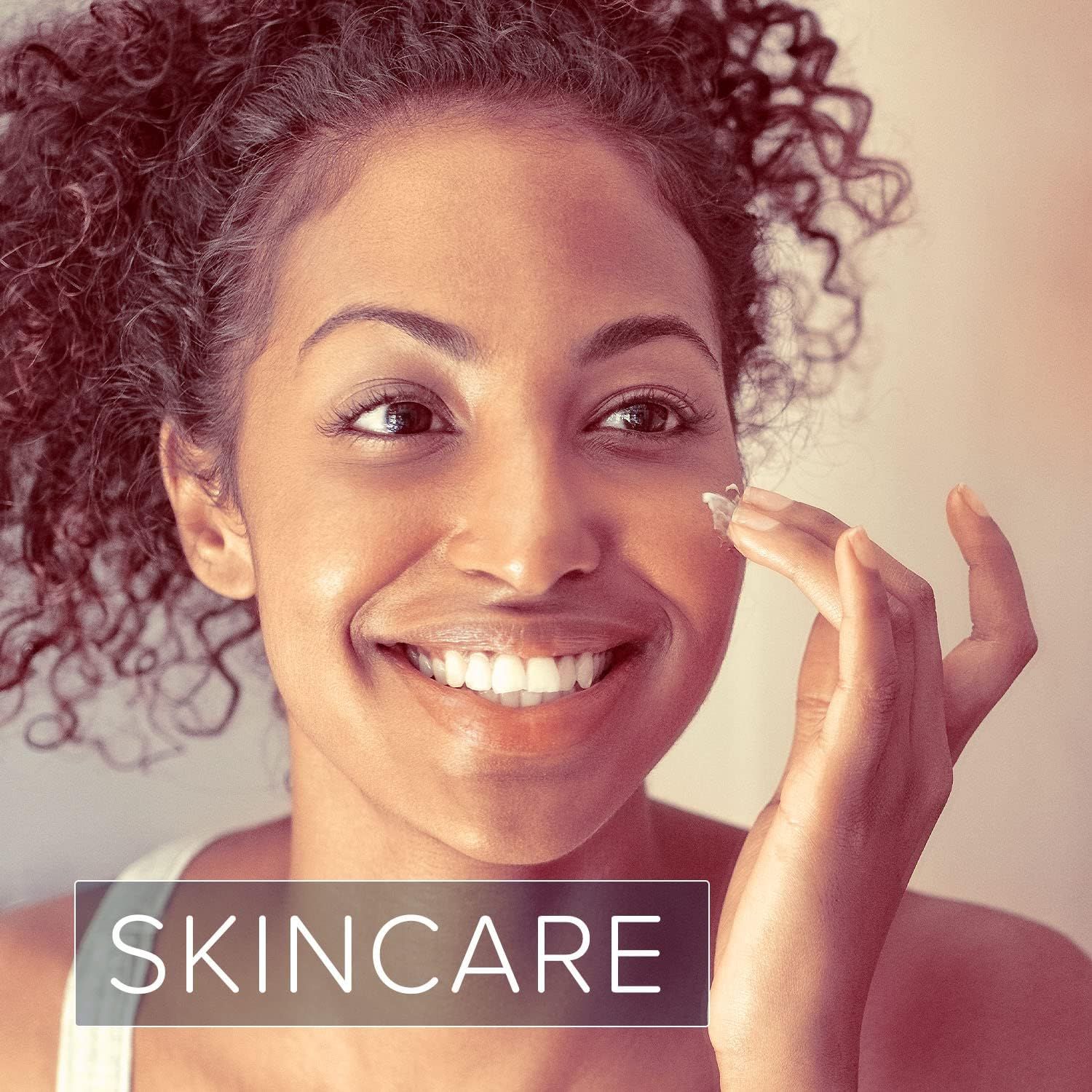 Frau trägt Creme auf das Gesicht auf. Lächelt. Text: SKINCARE.