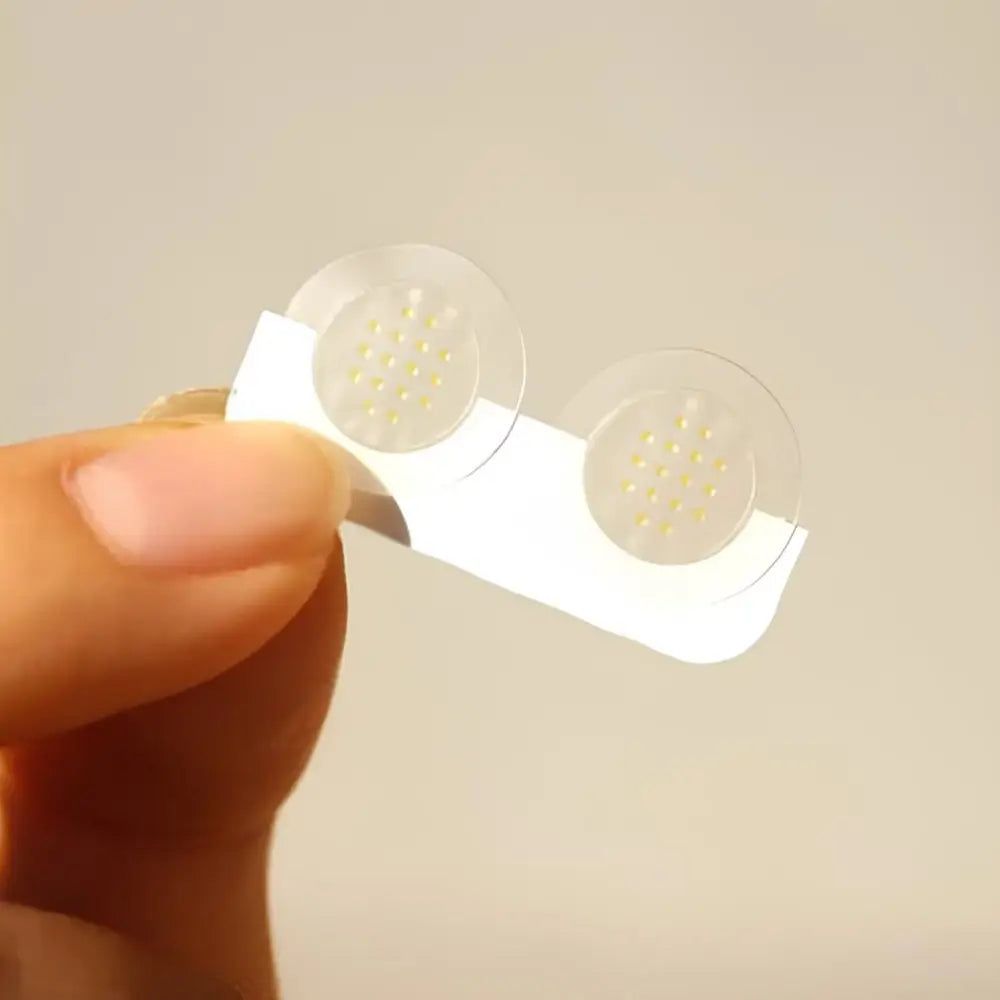 Zwei runde, transparente Pflaster mit gelben Punkten auf einem weißen Träger.
