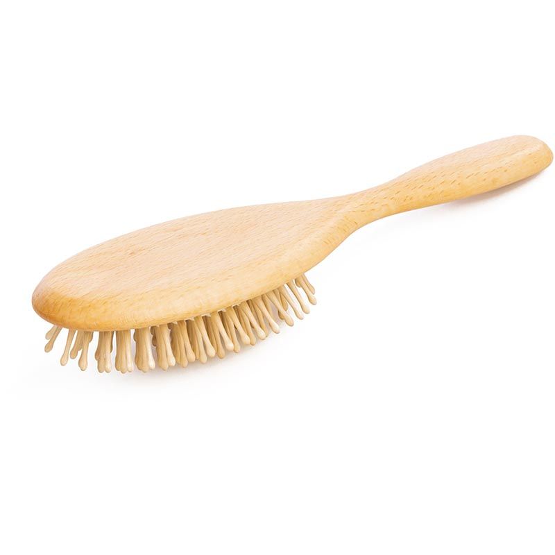 Ovale Holzbürste mit hellen Holzstiften. Der Griff ist hellbraun. Die Bürste liegt auf einer weißen Oberfläche.