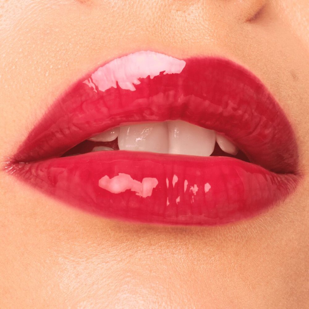 Nahaufnahme von Lippen mit rotem Lipgloss. Glänzendes Finish. Sichtbare Zähne.
