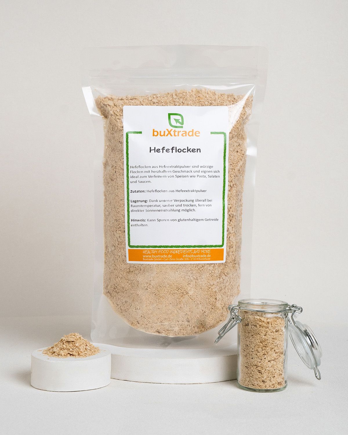 Bags of buXtrade Hefeflocken, one open with a small jar and pile of flakes.
