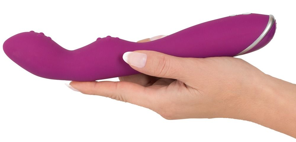 Lila Vibrator, gehalten in einer Hand. Silberne Akzente am Ende. Zwei Reizköpfe. Geformt für die Anwendung.