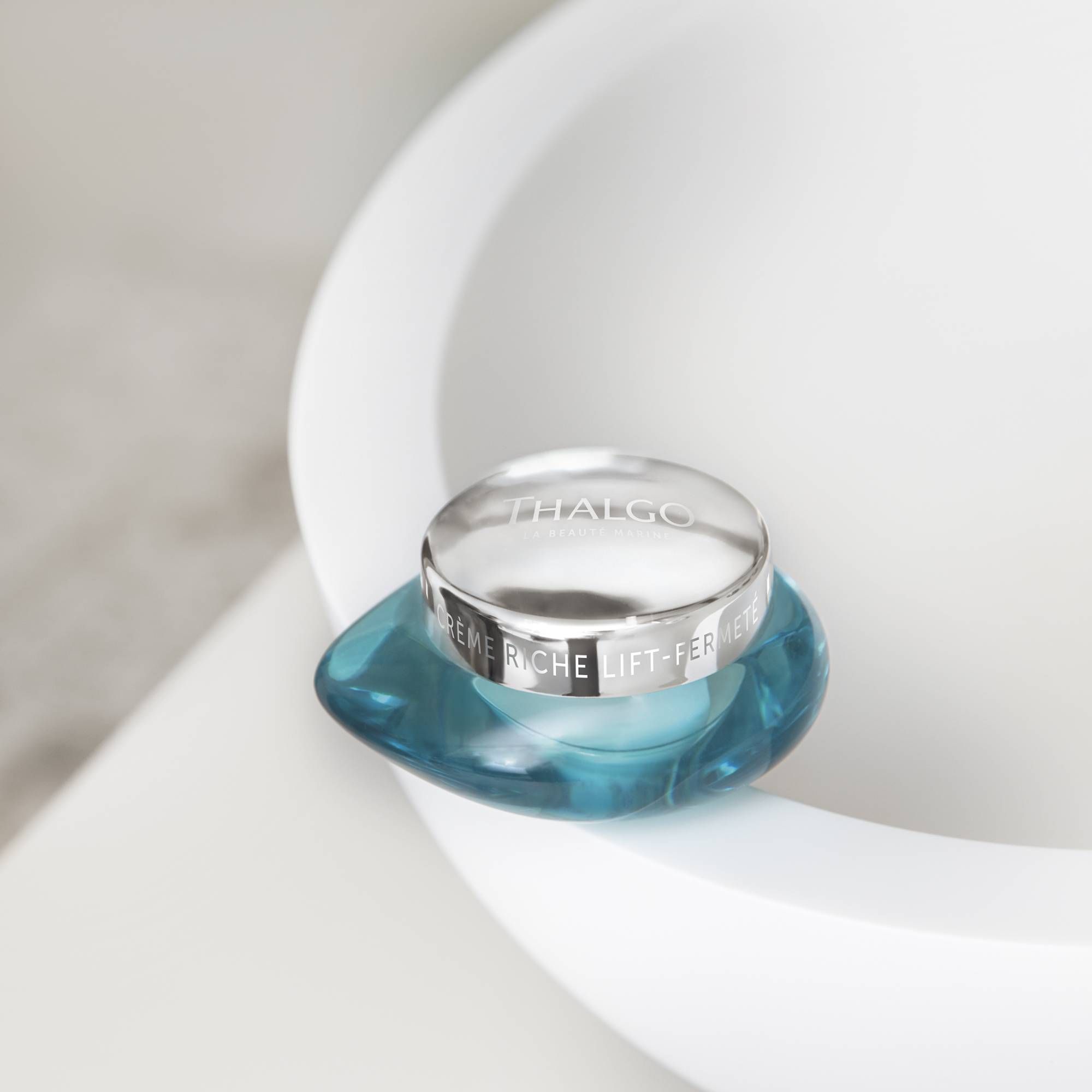 Türkisfarbener Tiegel mit silbernem Deckel. Aufschrift: THALGO und Crème Riche Lift-Fermeté.