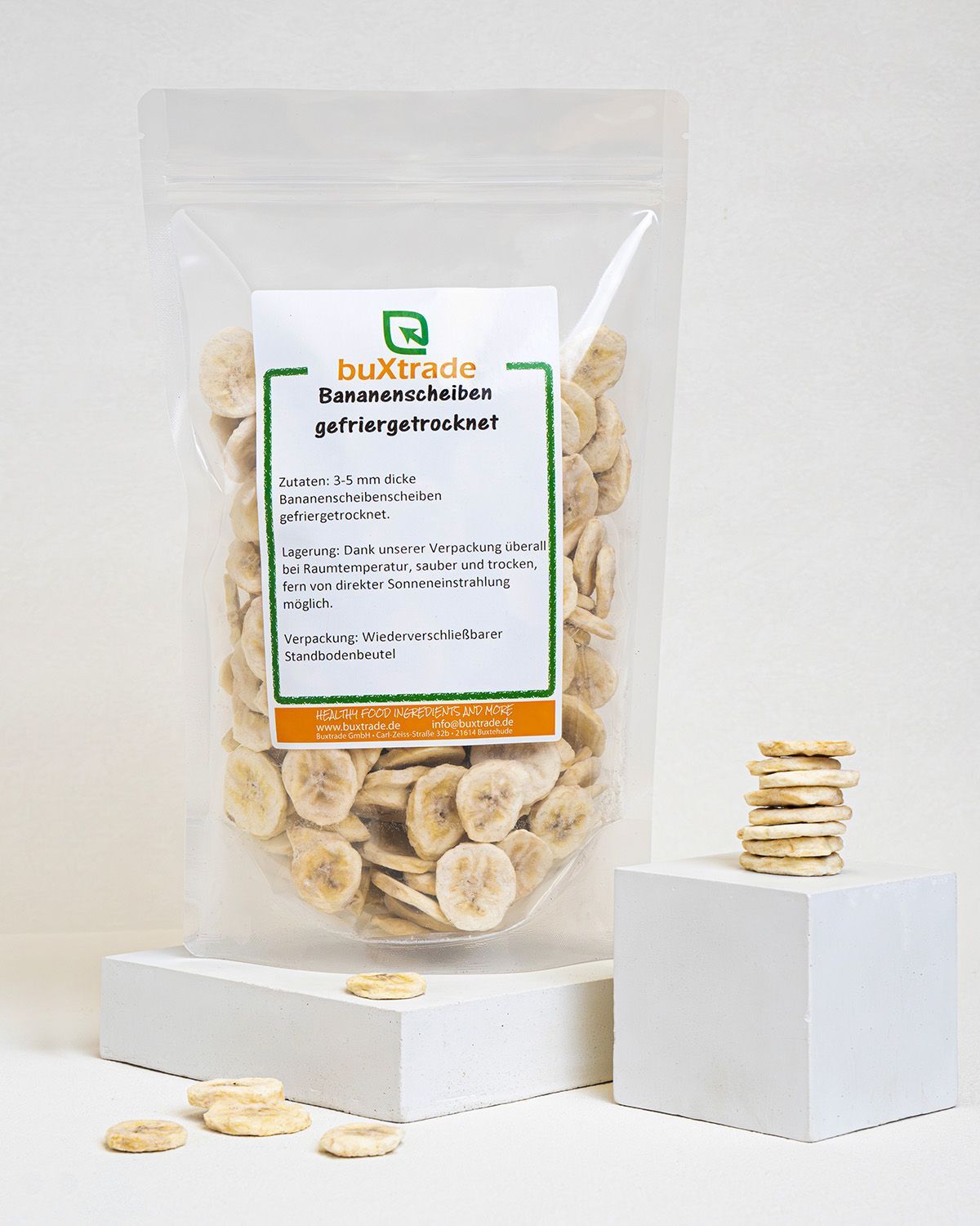 Verpackung mit gefriergetrockneten Bananenscheiben, daneben gestapelte Scheiben. Marke buXtrade.