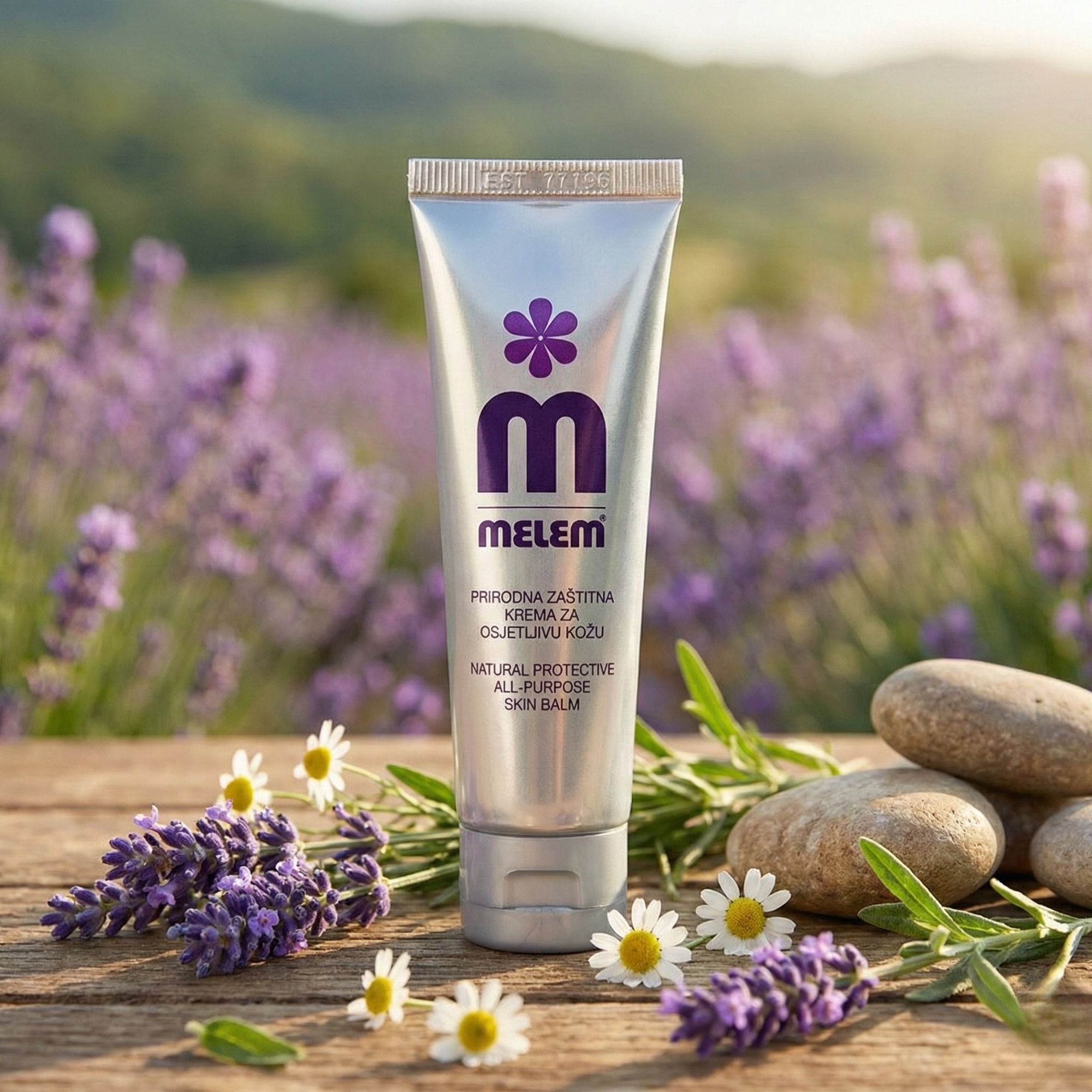 Silberne Tube mit lila Logo und Schriftzug MELEM auf Holz. Umgebung: Lavendel, Steine, Gänseblümchen.