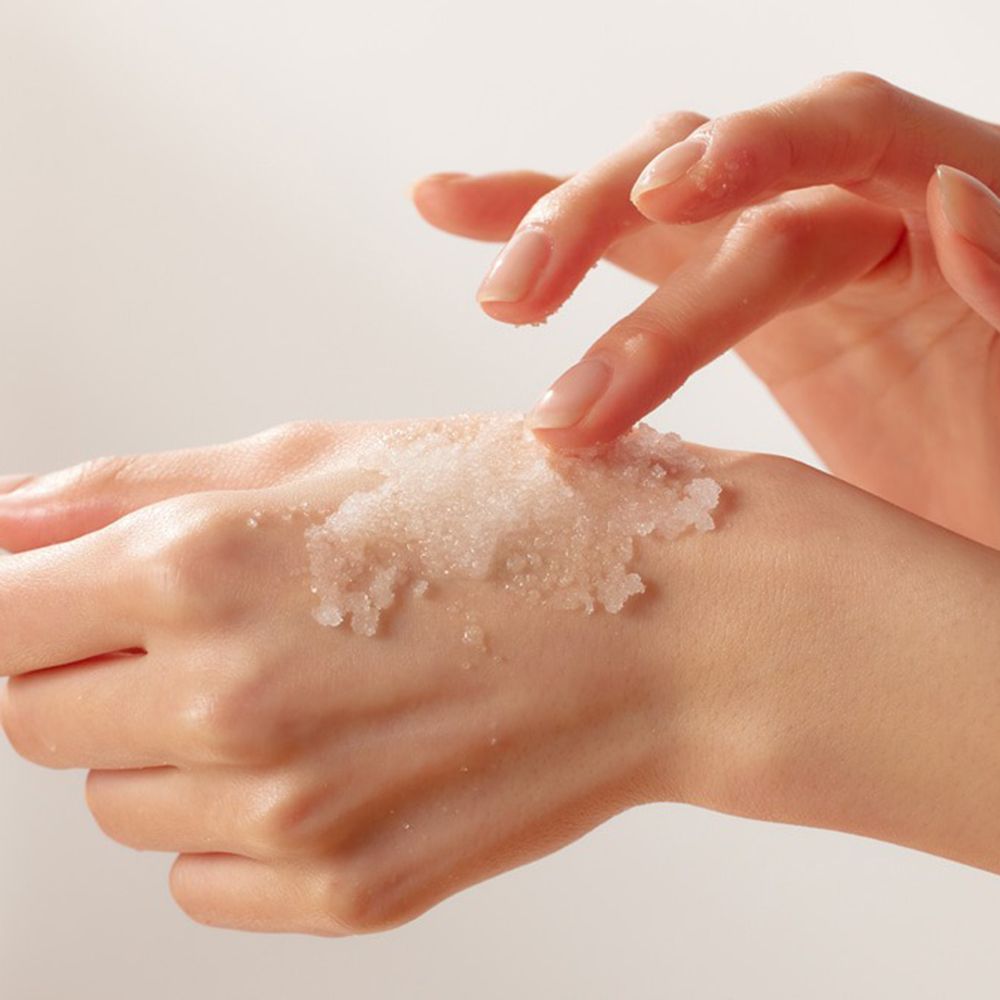 Hände mit Peeling. Das Produkt ist auf der Haut sichtbar.