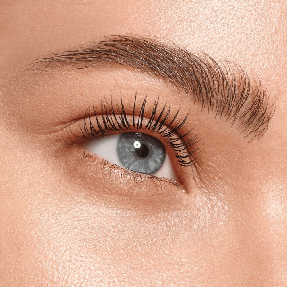 Nahaufnahme eines blauen Auges mit langen, getuschten Wimpern. Braune Augenbrauen.