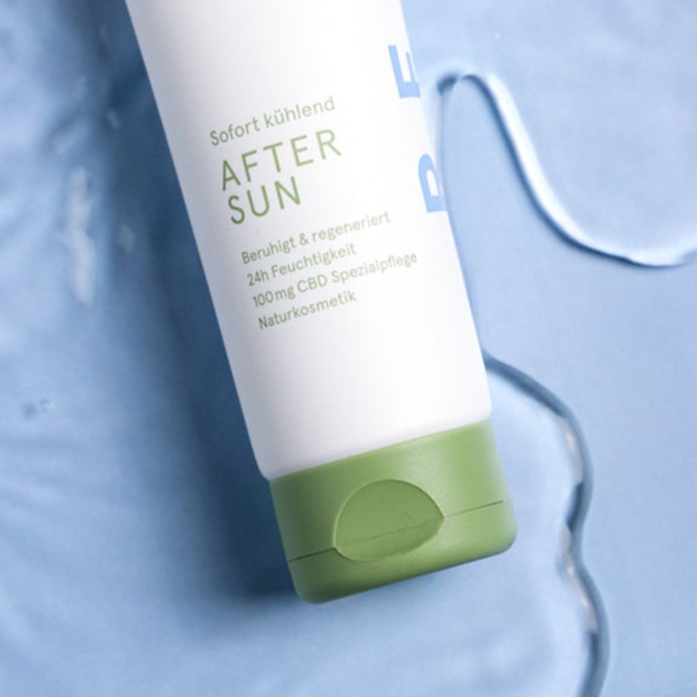 Nahaufnahme einer weißen Tube mit grünem Deckel. Aufschrift: AFTER SUN, sofort kühlend, beruhigt & regeneriert, 24h Feuchtigkeit, 100mg CBD Spezialpflege.