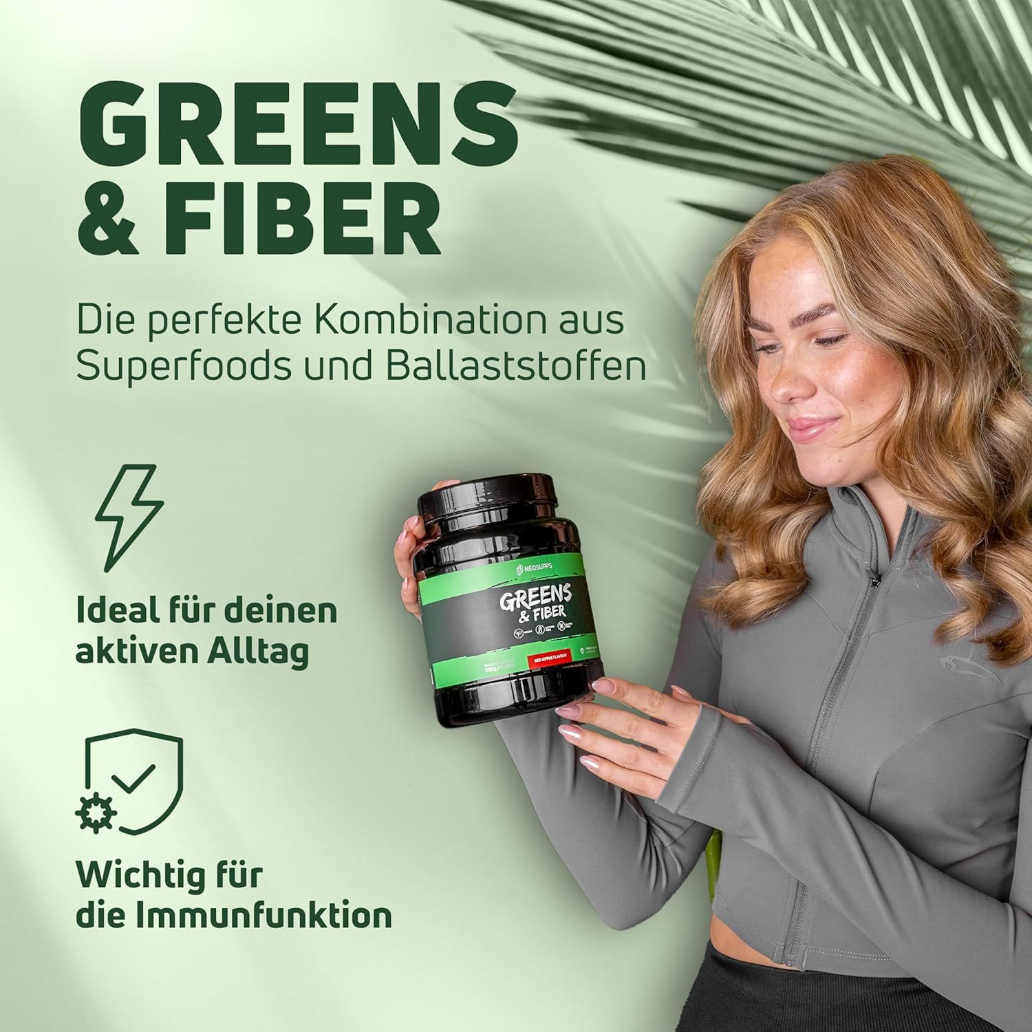 Frau hält Dose mit grünem Etikett. Aufschrift: Greens & Fiber. Icons: Energie, Immunsystem. Text: Die perfekte Kombination aus Superfoods und Ballaststoffen.