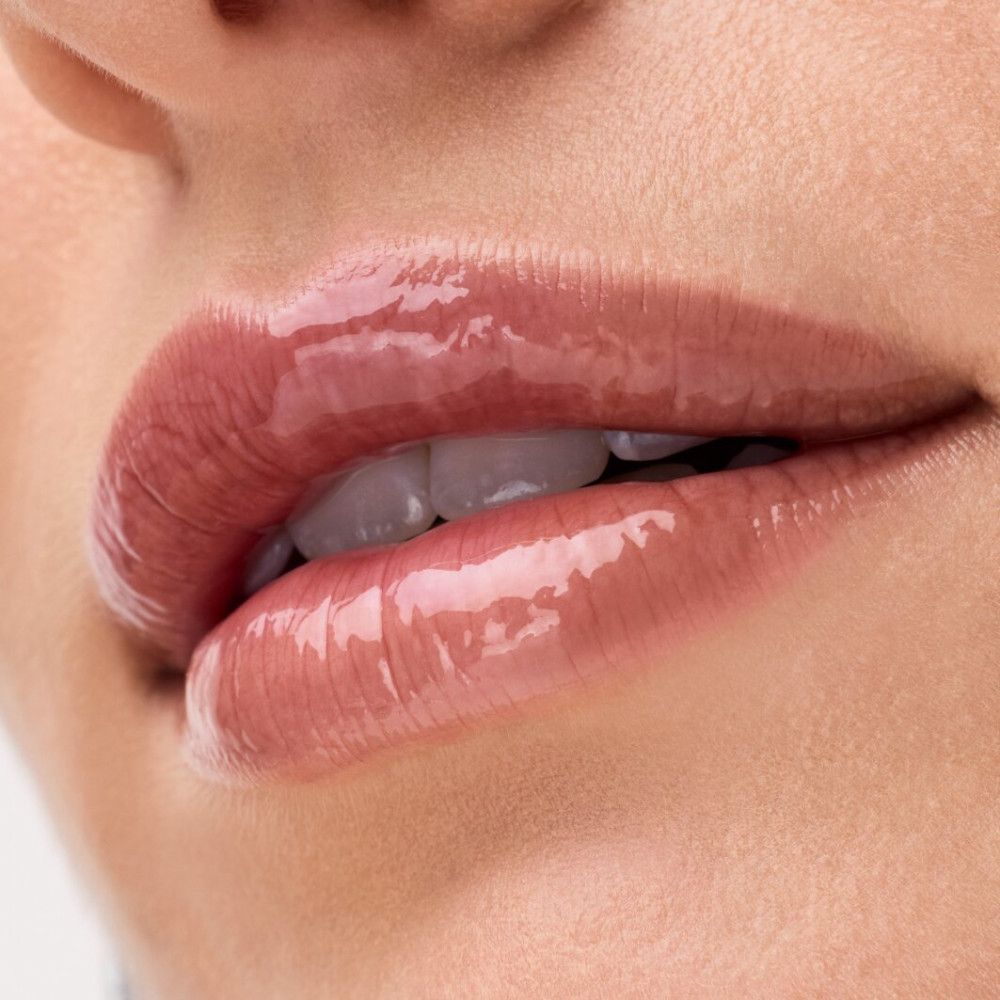 Nahaufnahme von Lippen mit glänzendem Lip Balm. Helle Haut, rosiger Farbton.