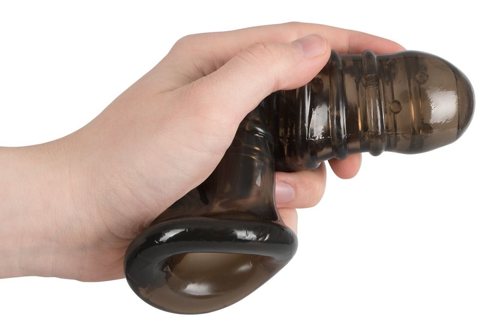 Schwarze Penishülle mit Öffnung für die Hoden, in einer Hand gehalten. Geriffelte Oberfläche, abgerundete Spitze.