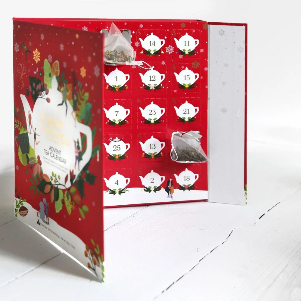 Adventskalender, geöffnet, mit Teeblättern und Teebeuteln. 25 nummerierte Fenster. Roter Hintergrund.