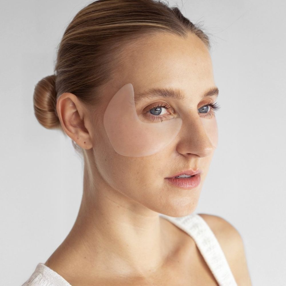 Gesicht einer Frau mit Augen-Schläfen Pads. Pads sind transparent und auf der Haut sichtbar.