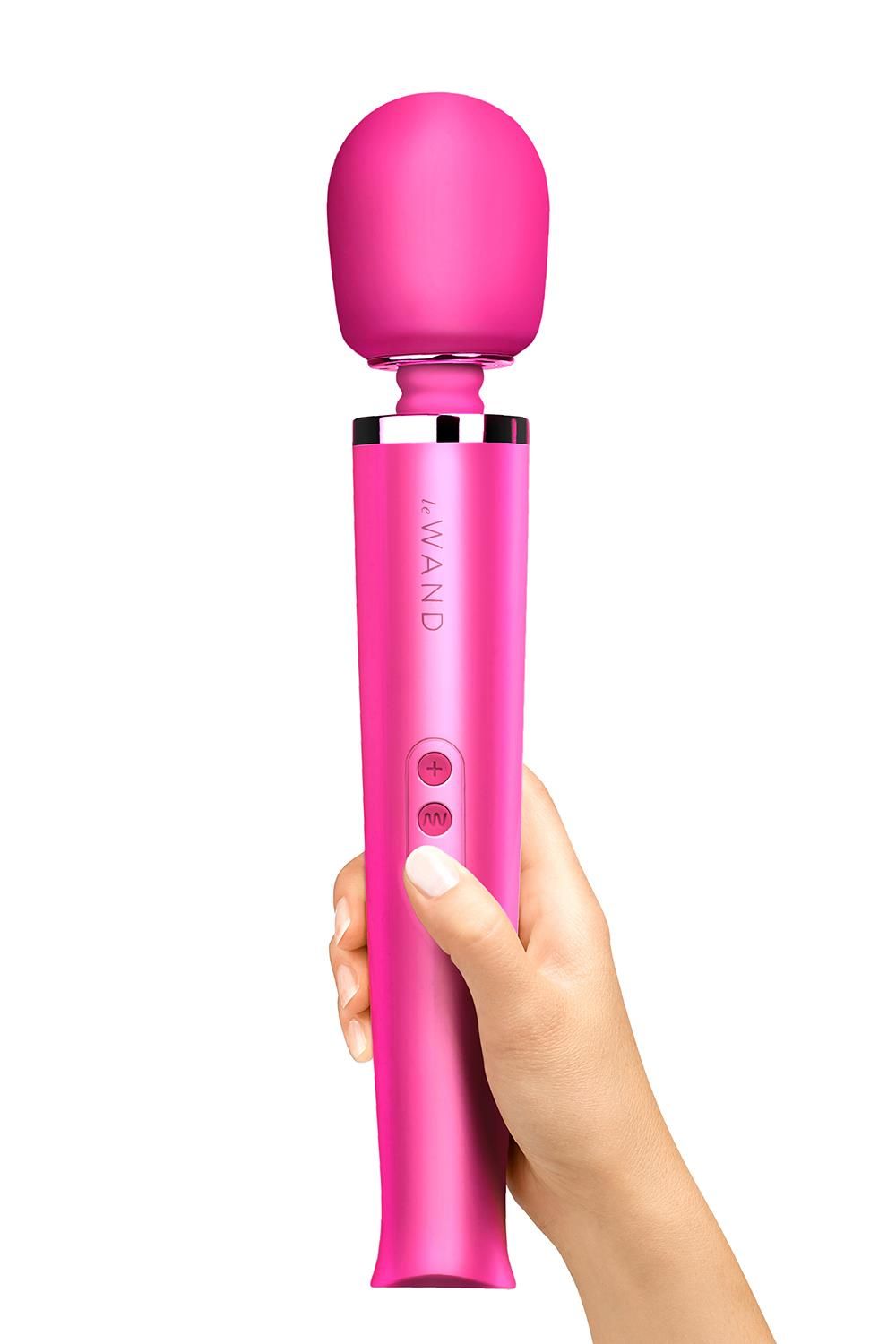 Magentafarbener Massagestab mit abgerundetem Kopf, gehalten von einer Hand. Auf dem Griff sind Tasten und der Schriftzug "Le Wand" zu sehen.