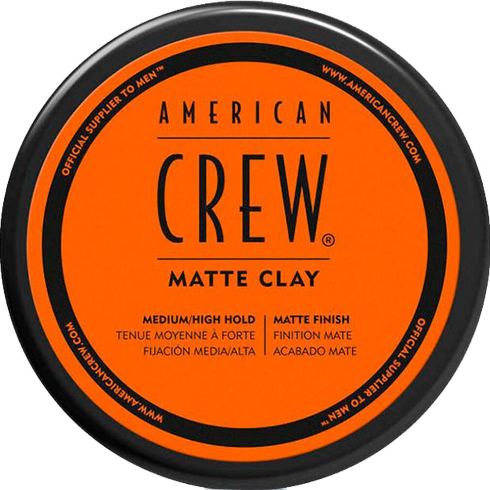 Runde, schwarze Dose mit orangefarbenem Deckel. Schwarzer Schriftzug: AMERICAN CREW. Text: Matte Clay, Medium/High Hold, Matte Finish.