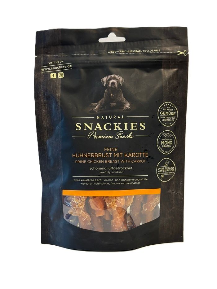 Verpackung von Snackies Feine Hühnerbrust mit Karotte. Schwarze Tüte mit Produktabbildung und Text. Sichtfenster mit getrocknetem Fleisch.