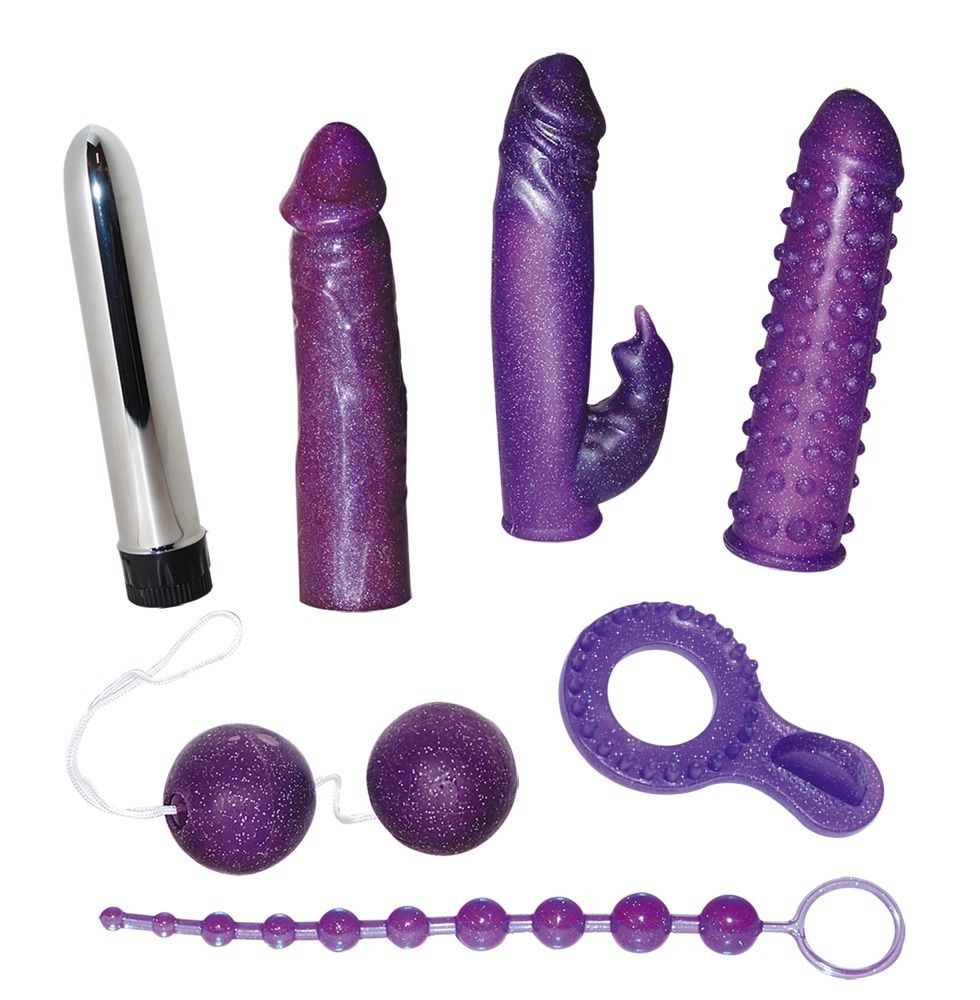 Sieben violette Sextoys: Vibrator, zwei Dildos, ein Dildo mit Noppen, zwei Kugeln mit Schnur, ein Ring mit Noppen und eine Perlenkette.