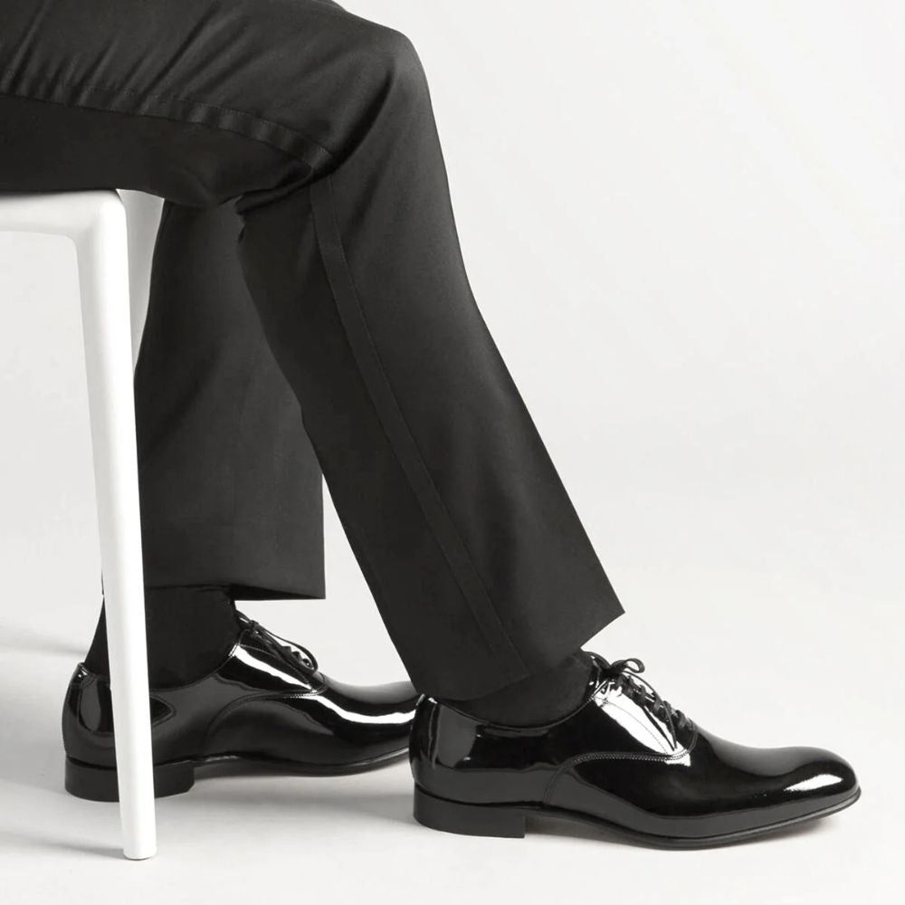 Mann in schwarzer Hose und schwarzen Schuhen. Schwarze Kompressionsstrümpfe sind sichtbar.