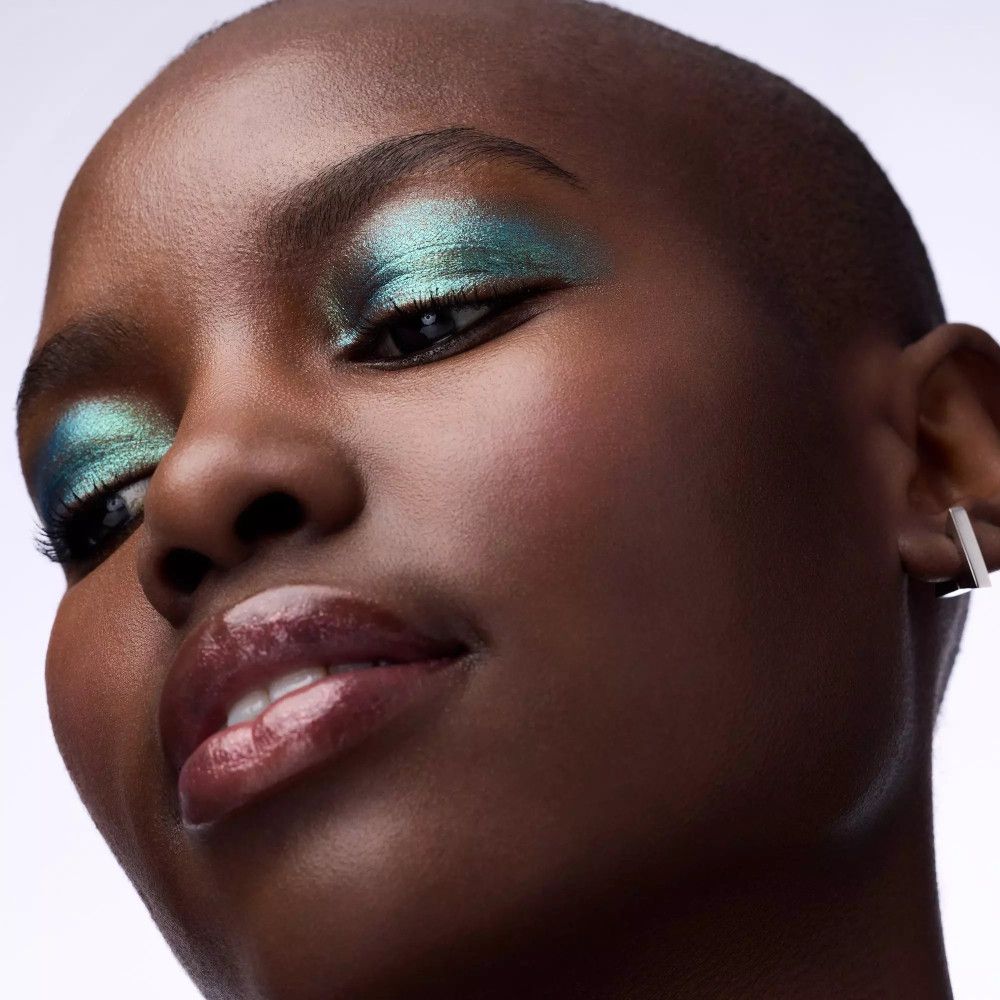 Porträt einer Frau mit grünem Lidschatten. Glänzende Lippen. Kurze Haare.