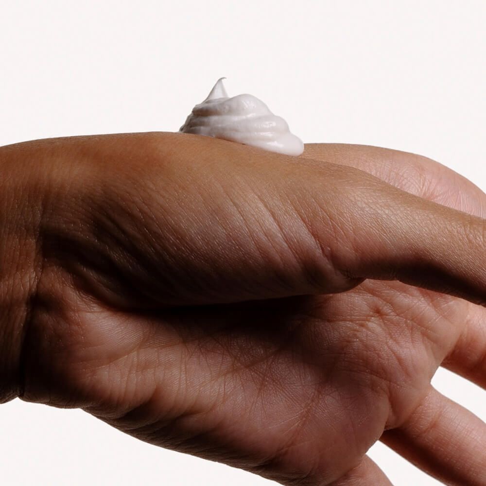 Hand mit Creme. Weiße Creme auf der Haut. Helle Hautfarbe.