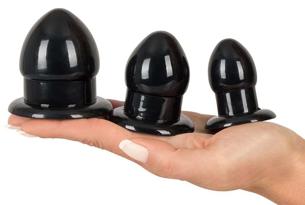 Drei schwarze Anal-Stretching-Plugs. Kegelförmig mit breiter Basis. Gehalten in einer Hand.