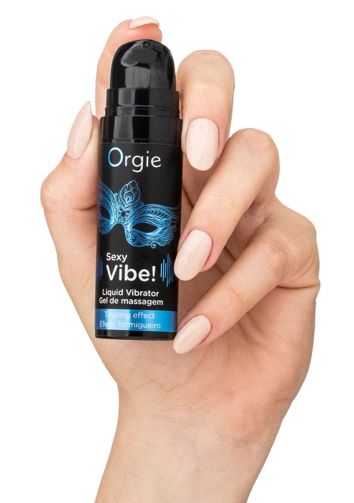 Hand hält schwarze Flasche mit blauem Maskenmotiv. Text: Sexy Vibe!, Gel de massage. Beige Nägel.