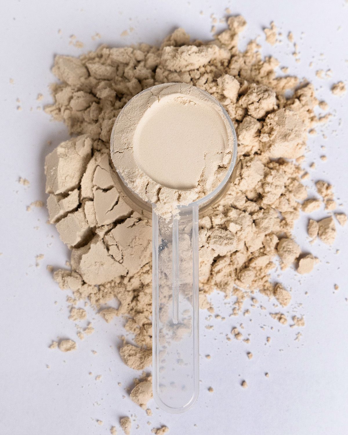 Ein Messlöffel gefüllt mit hellem Pulver, liegt auf einem Haufen Pulver.