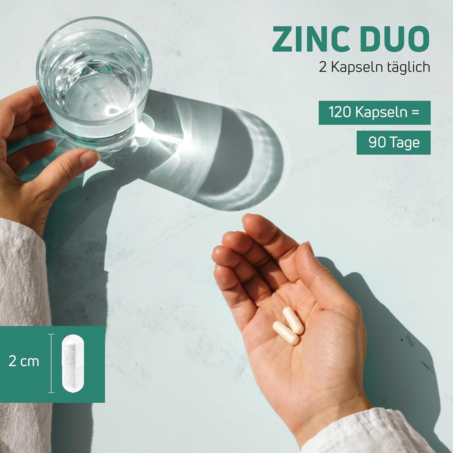 Hände halten Kapseln und Glas Wasser. Text: "ZINC DUO", "2 Kapseln täglich", "120 Kapseln = 90 Tage". Kapsel mit 2 cm.