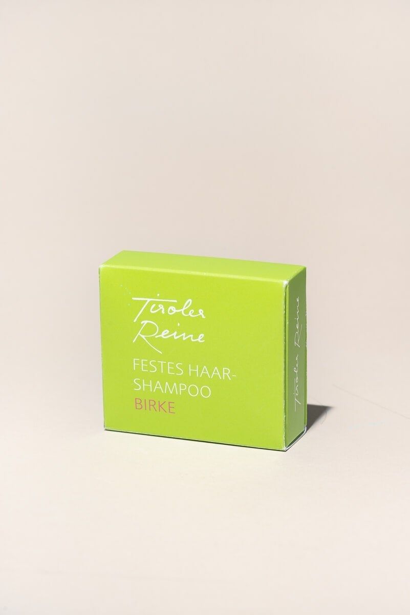 Grüne Schachtel mit weißem Schriftzug. Aufschrift: Tiroler Reine, festes Haarshampoo Birke. Eckige Form, helle Oberfläche.