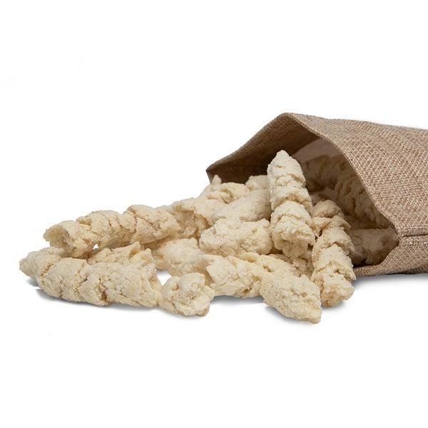 Haufen von BIO Kokos Sticks, aus einem Beutel herausgefallen. Helle, zylindrische Snacks. Auf weißem Hintergrund.