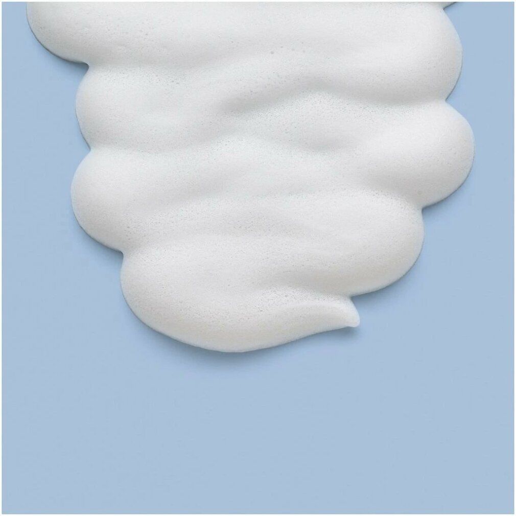 Nahaufnahme von weißem Mousse auf hellblauem Hintergrund. Schaumstruktur mit wellenförmigen Konturen.