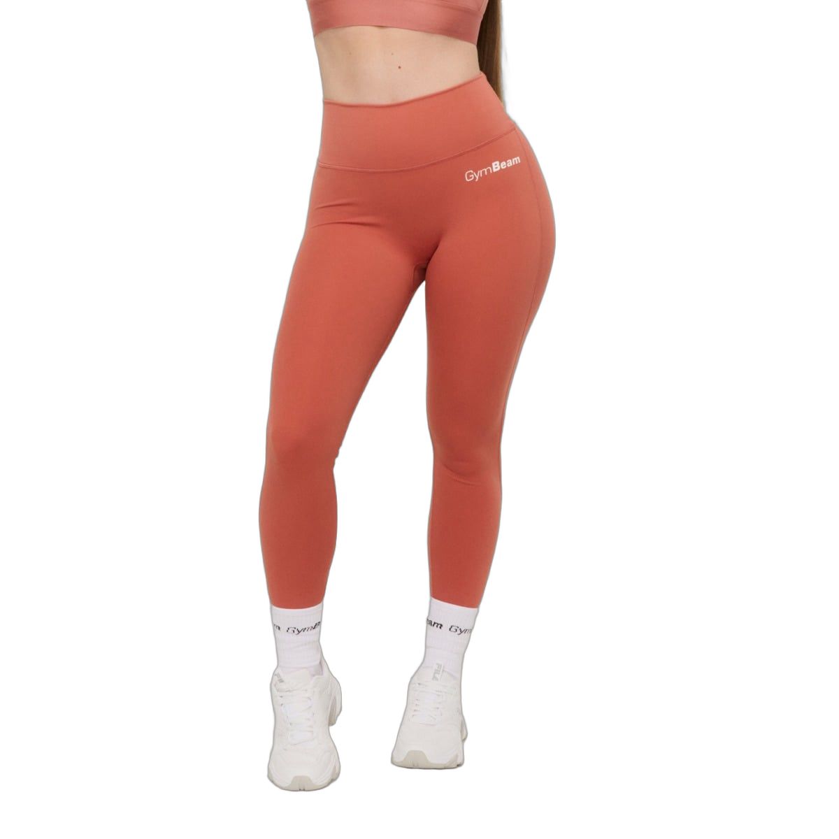 Vorderansicht einer Frau in knöchellangen, zimtfarbenen Leggings mit hohem Bund und ohne vordere Naht.