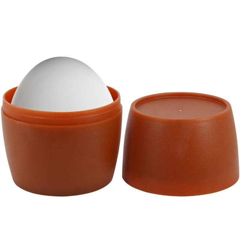 Masturbator in Eiform in einem braunen Behälter. Deckel daneben. Weißes Produkt, brauner Behälter.