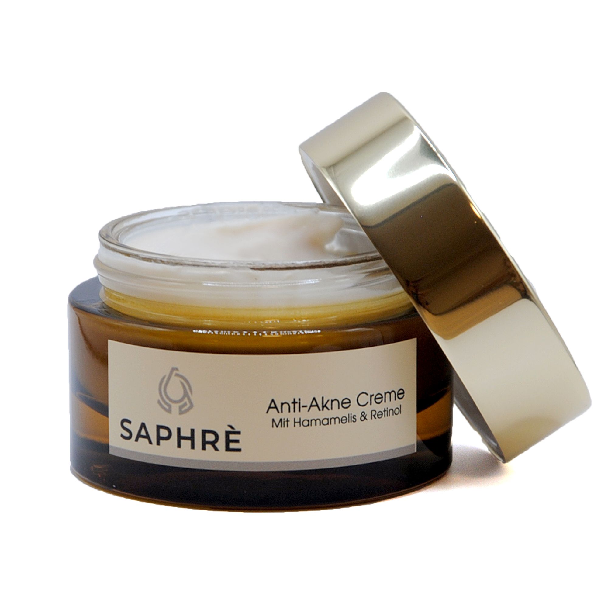 Braunes Glas mit geöffnetem goldfarbenem Deckel. Creme sichtbar. Etikett "SAPHRE" und "Anti-Akne Creme".