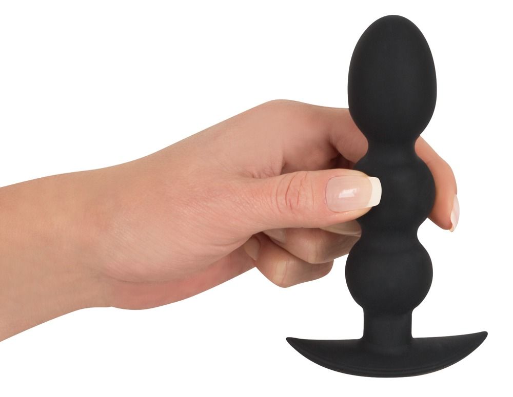 Hand hält einen schwarzen Analplug mit drei Kugeln und breitem Flansch.