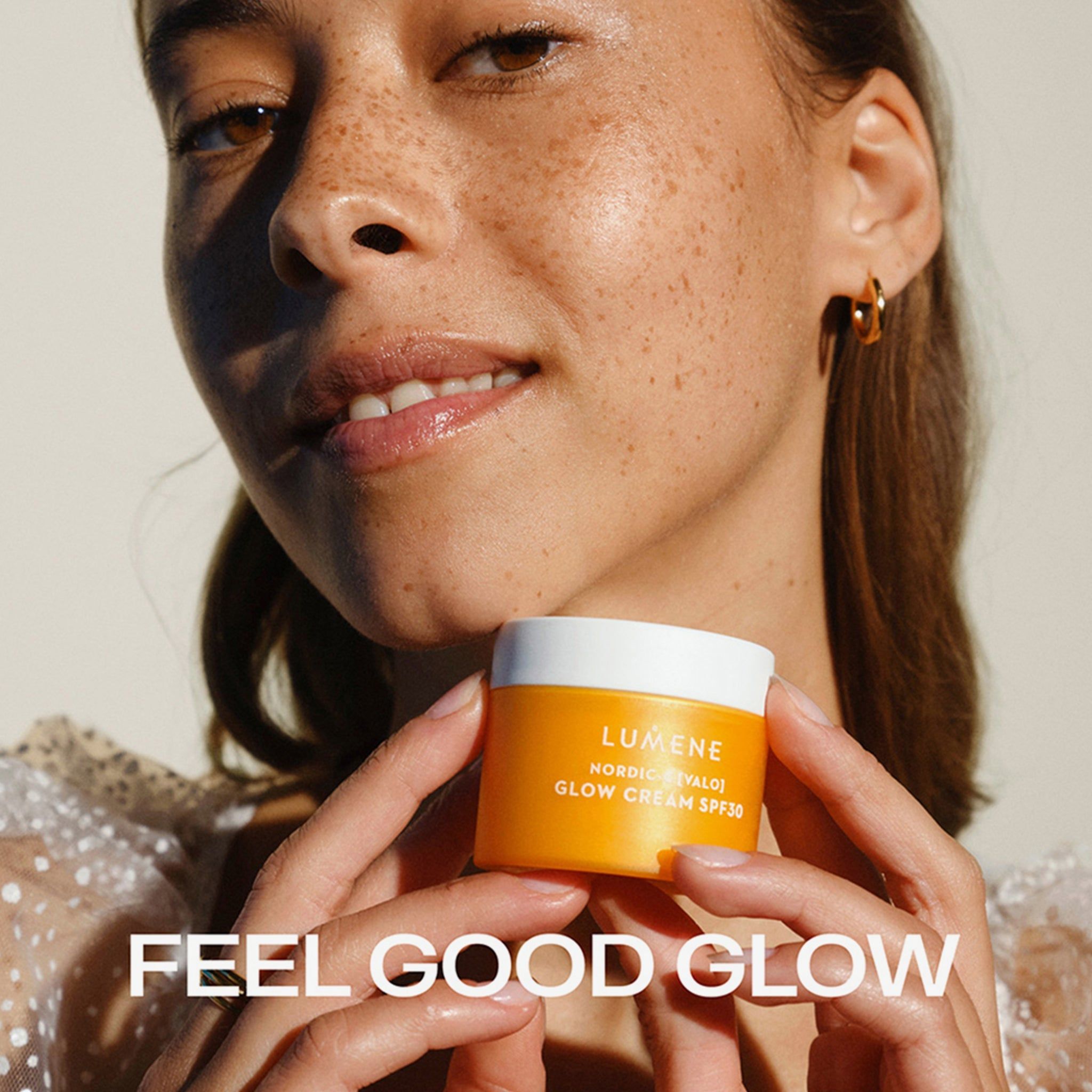 Frau hält eine gelbe Creme-Dose. Aufschrift: LUMENE, NORDIC-C [VALO] GLOW CREAM SPF30. Text: FEEL GOOD GLOW.