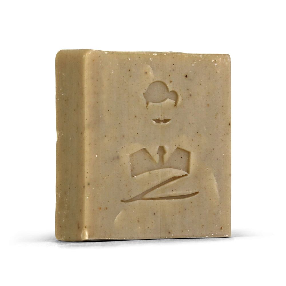 Rechteckige Seife mit eingeprägtem Logo. Helle Farbe, sichtbare Partikel. Produkt für Bart und Haar.