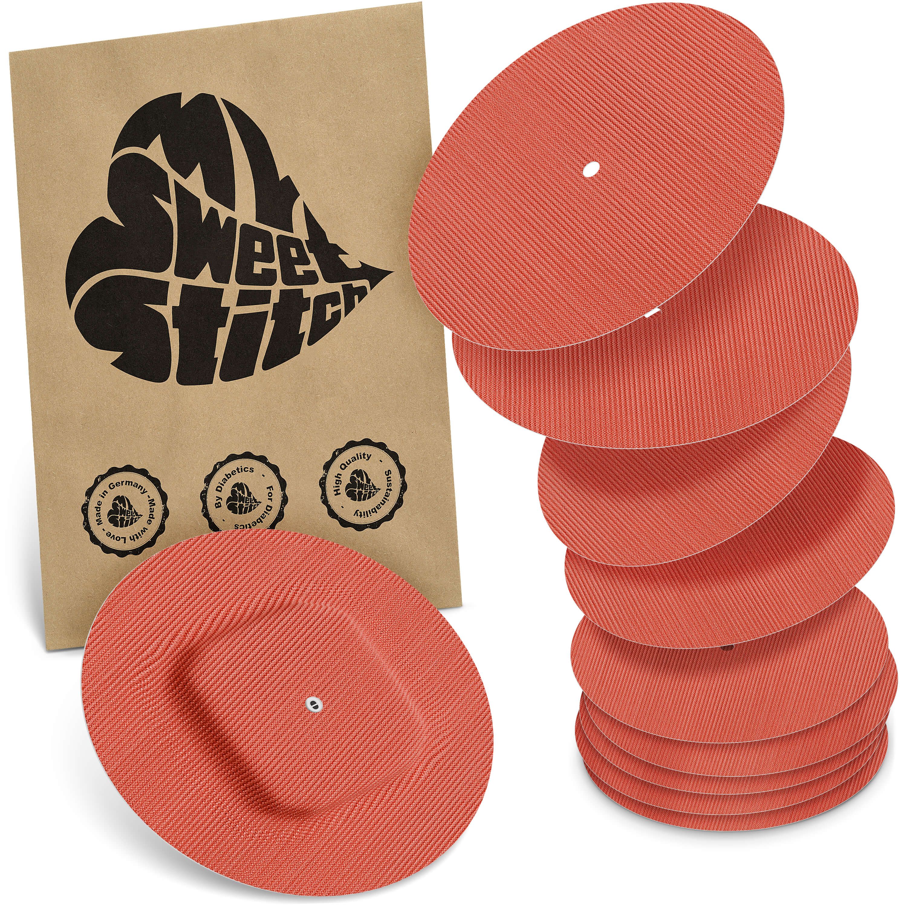 Runde, korallenfarbene Pflaster mit geriffelter Oberfläche. Verpackung mit Logo und Siegeln. Mehrere Pflaster gestapelt.