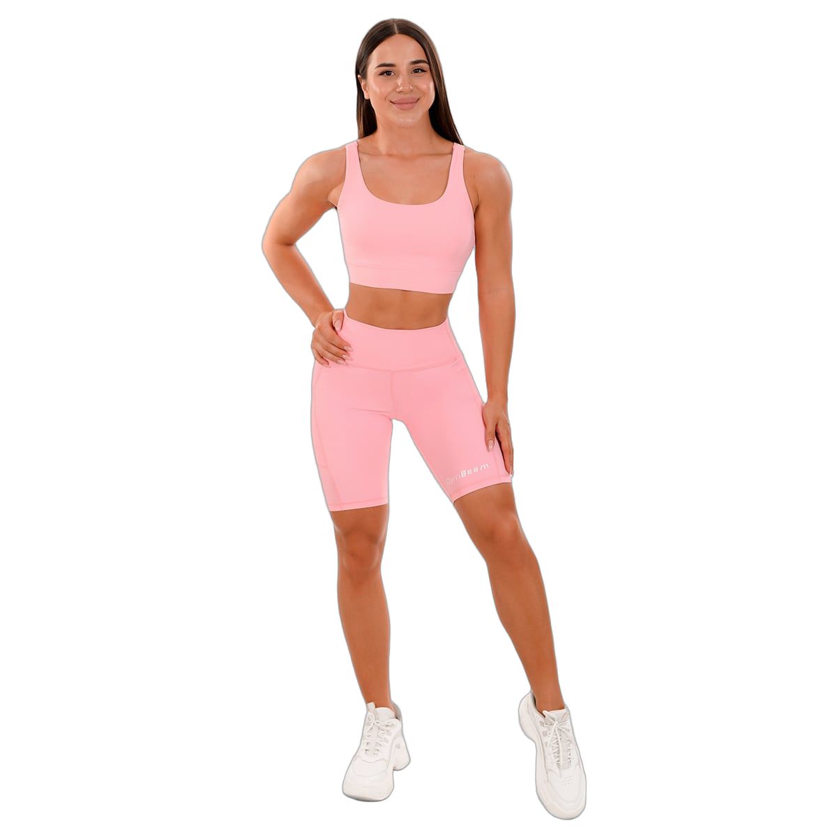 Frau in pinken Biker-Shorts und Sport-BH mit GymBeam-Logo.