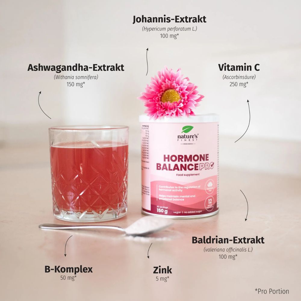 Rosa Dose "Nature's Finest Hormone Balance PRO" neben Glas mit roter Flüssigkeit, Löffel, Blumen und Zutaten.
